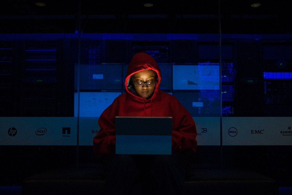 Developer writing code on a laptop in a dark room